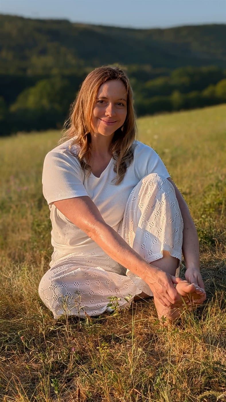Ivana Černíková sedí na louce a drží si chodidlo